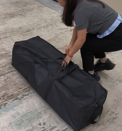 Portable black carry bag containing a circular trade show hanging banner frame and fabric graphic