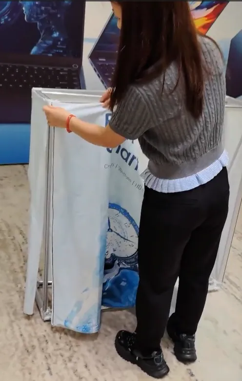 Positioning a dye-sublimated stretch-fabric graphic around a pop-up counter frame