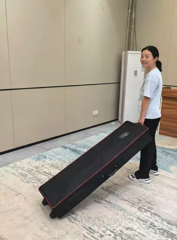 One person moving a portable display in a wheeled bag